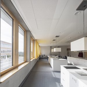 Lichtdurchfluteter, weitläufiger Raum mit Holzfenstern und modernen Kochfeldern mit Spülbecken.